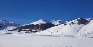 Ski slopes and lifts at a winter mountain resort in Abruzzo under a bright blue sky.