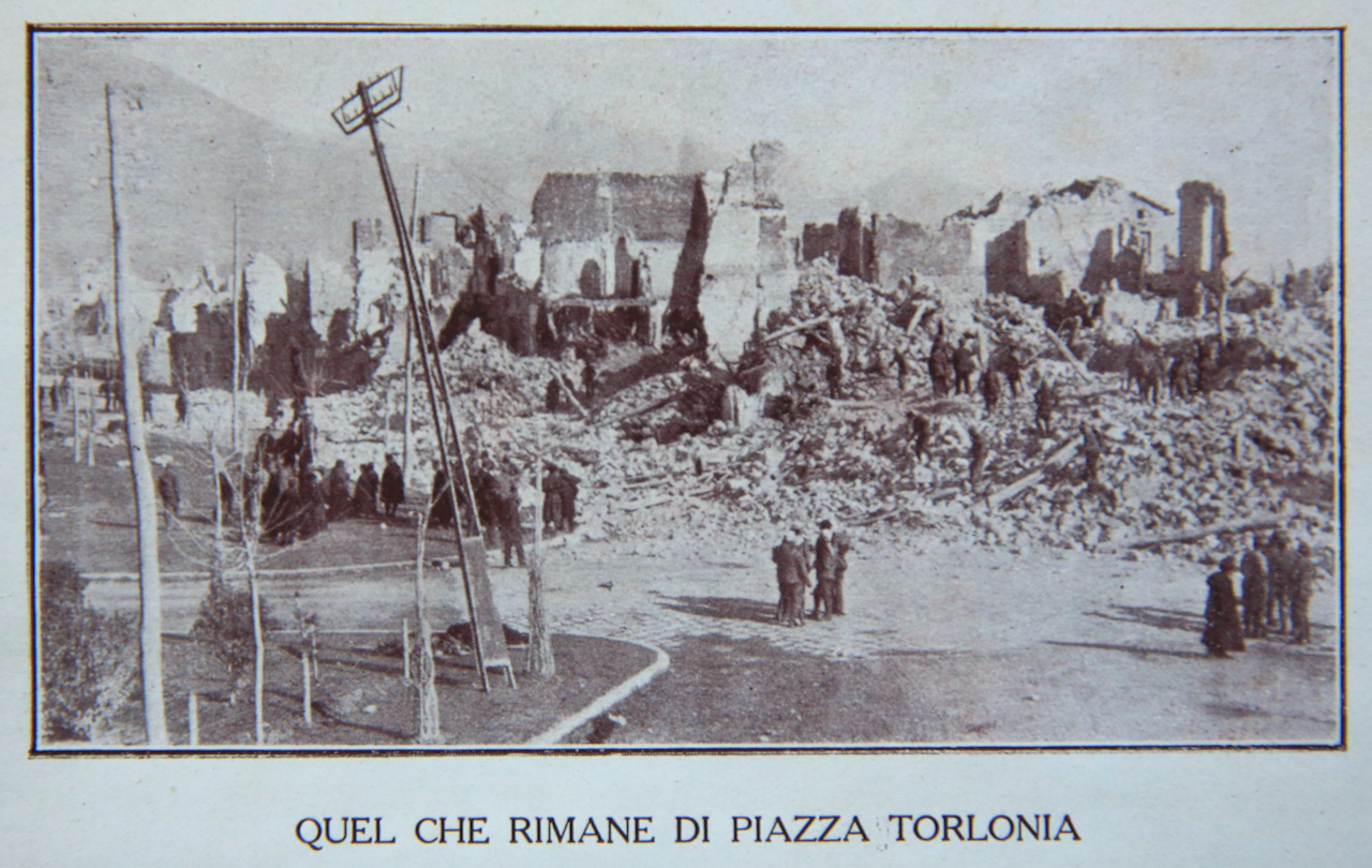 Sepia-toned photo of Piazza Torlonia ruins with damaged buildings and debris.